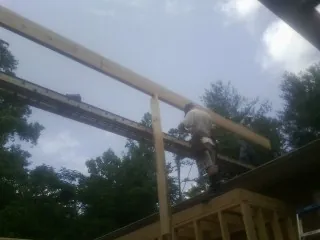 Carpenter setting a ridge beam over a new addition frame — Ice Dam Removal by Roofing Brothers in Bunch