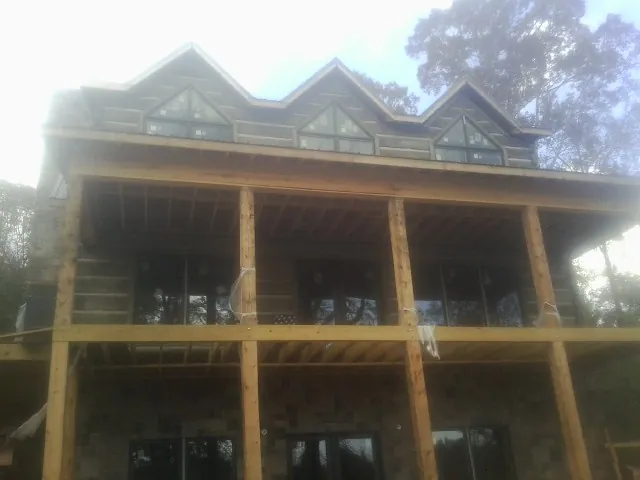 Dormers and porch framing on a large log home under construction — Roof Coating work by our crew in Bunch