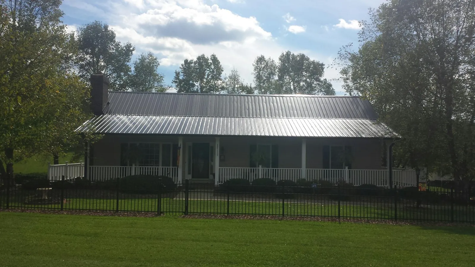 Gray metal roof on a brick ranch with a full width front porch — Gutter Guard Installation work by our crew in Bunch