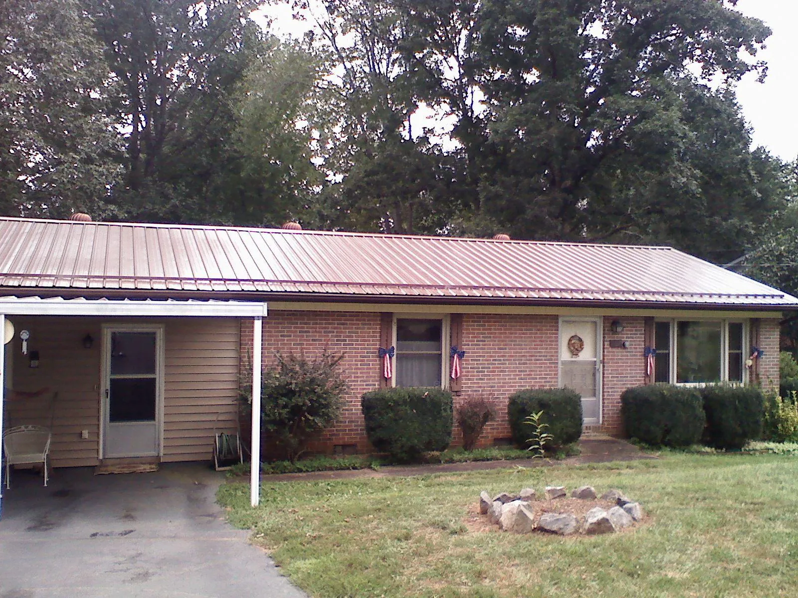 Bronze metal roof and carport on a brick ranch home — Roof Repair work by our crew in Bunch