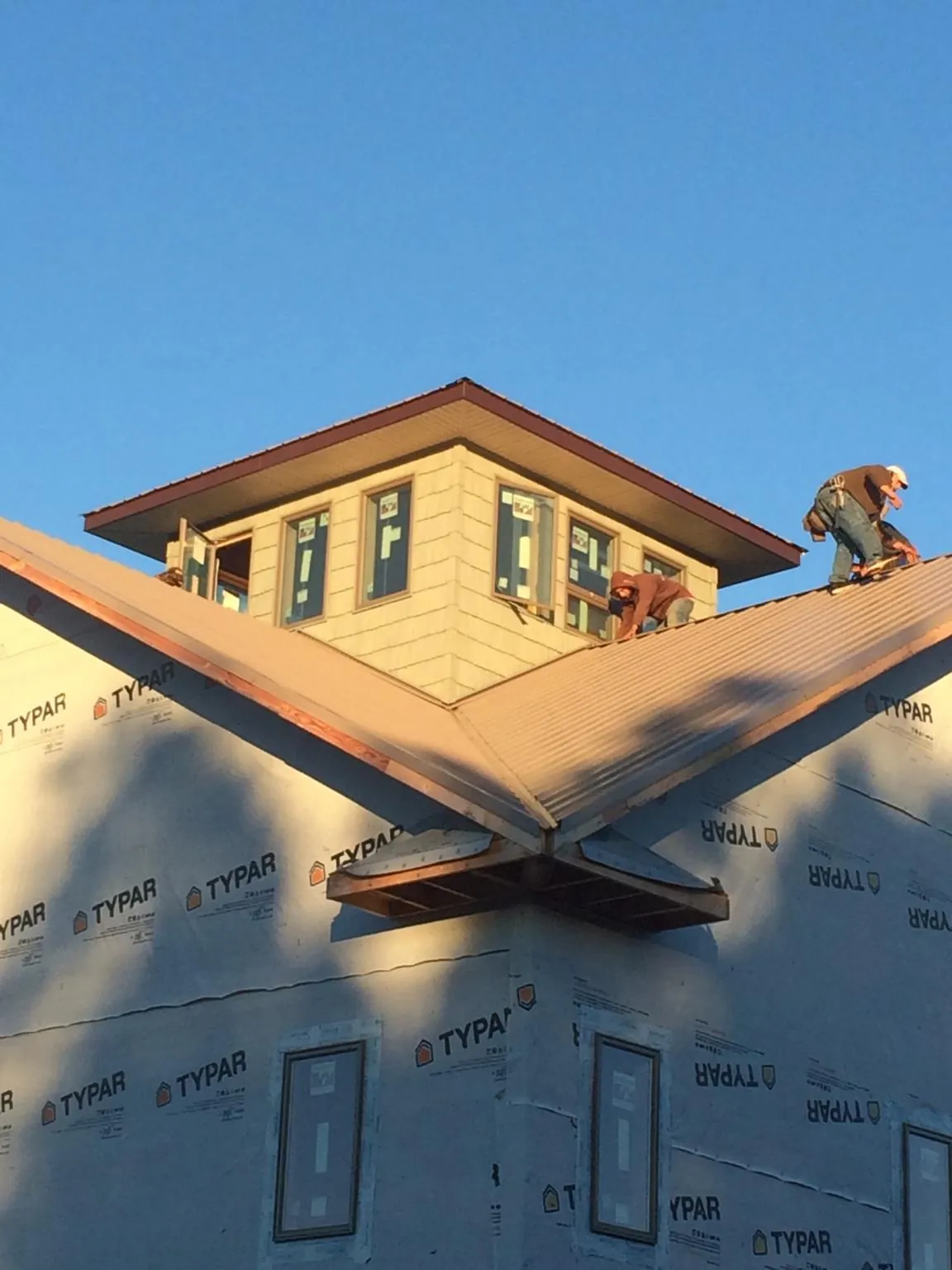 Roofers working around a rooftop cupola on a new metal roof at sunset — Roof Waterproofing in Bunch by Roofing Brothers